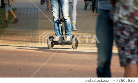 Teenage boy in jeans riding hyroscooter outdoors. 72603680