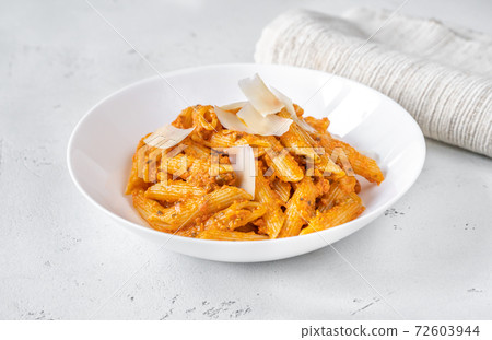Portion of penne pasta with orange pesto sauce 72603944