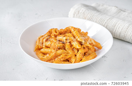 Portion of penne pasta with orange pesto sauce 72603945