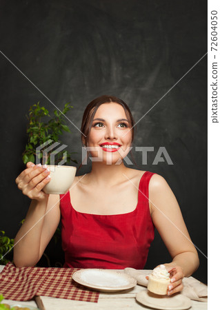 Attractive brunette woman drinking coffee and eating cupcake in restaurant 72604050