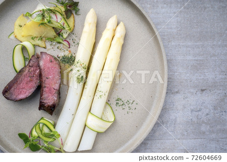 dry aged sliced fillet steak with white asparagus in hollandaise sauce and roast potatoes  72604669