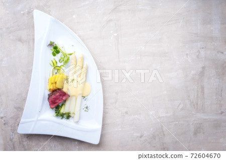 dry aged sliced fillet steak with white asparagus in hollandaise sauce and roast potatoes 72604670