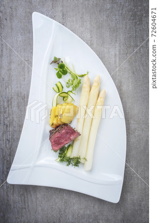 dry aged sliced fillet steak with white asparagus in hollandaise sauce and roast potatoes 72604671