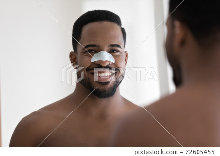 Happy african ethnicity man cleansing pores with removal strip. 72605455