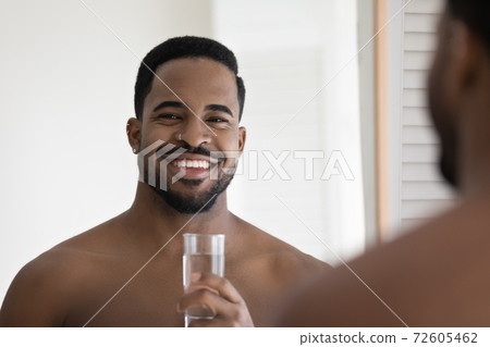 Smiling bare african american man holding glass of water. Smiling bare african american man holding glass of water. 72605462