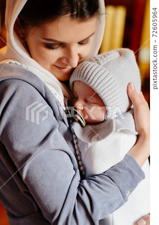 beautiful mom in a headscarf with a small child in her arms in church.  72605964