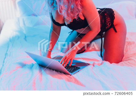 Beautiful, young girl posing in front of a web camera, working as a sexual model. The concept of online flirting, sex on the Internet. Beautiful, young girl posing in front of a web camera, working as a sexual model. The concept of online flirting, sex on the Internet. 72606405