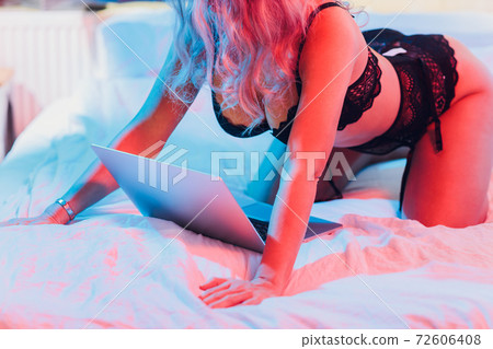 Beautiful, young girl posing in front of a web camera, working as a sexual model. The concept of online flirting, sex on the Internet. 72606408