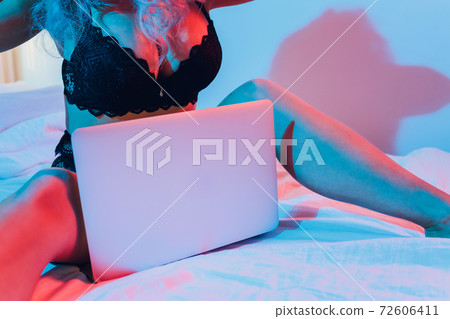 Beautiful, young girl posing in front of a web camera, working as a sexual model. The concept of online flirting, sex on the Internet. 72606411