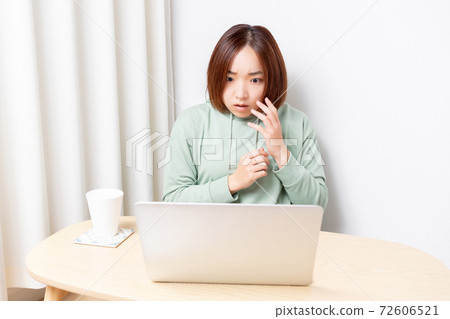 A woman who is surprised while using a laptop 72606521