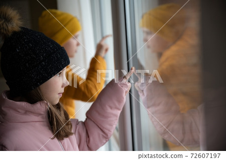 Sad children stand by the window and miss a normal life. 72607197