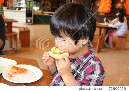 男孩在一家餐館吃披薩 72609029