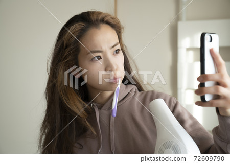 A woman drying her hair with a hair dryer 72609790
