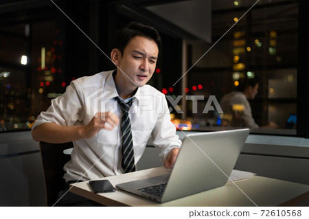 A businessman who works overtime late at night in the office A businessman who works overtime late at night in the office 72610568