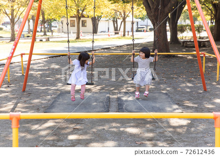 Girl playing on a swing with friends 72612436
