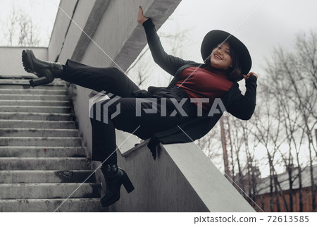 Brunette woman in hat sits and enjoys on the stairs of building in city Brunette woman in hat sits and enjoys on the stairs of building in city 72613585
