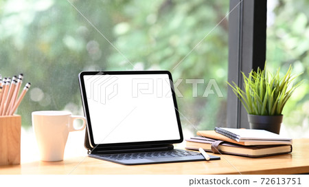 Cropped shot of tablet with smart keyboard, coffee cup, pencils and book on workspace table.Blank screen for graphics display montage. 72613751