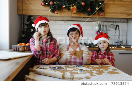 Grandma and her granddaughters make cookies in the kitchen Grandma and her granddaughters make cookies in the kitchen 72613834