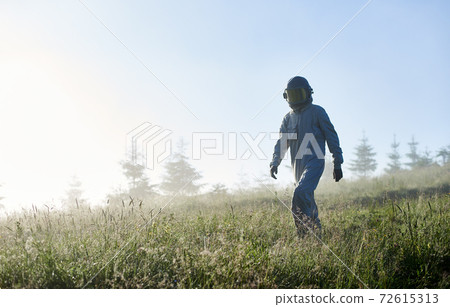 Space traveler walking through the grass. 72615313