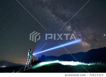 Space traveler shining flashlight into majestic night sky. Space traveler shining flashlight into majestic night sky. 72615325