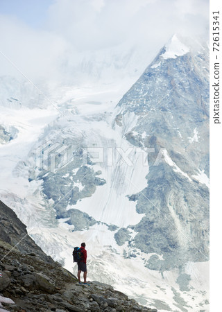 Male tourist climbing snowy rocky cliffs of beautiful Penning Alps in Switzerland Male tourist climbing snowy rocky cliffs of beautiful Penning Alps in Switzerland 72615341