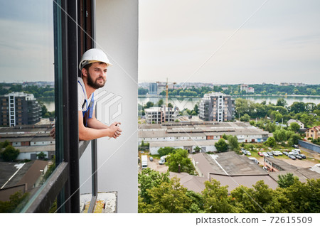 Male worker leaning out of the window. Male worker leaning out of the window. 72615509