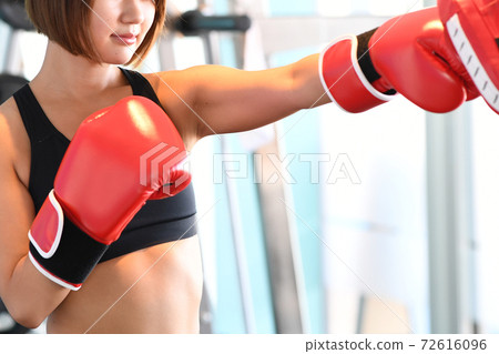 Young woman hitting a mitt in the gym Young woman hitting a mitt in the gym 72616096
