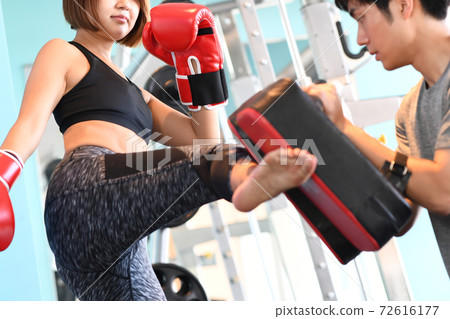A woman and a trainer kicking a mitt A woman and a trainer kicking a mitt 72616177