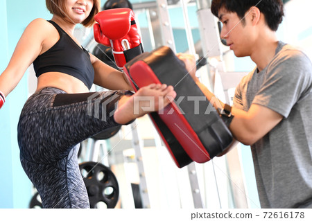 A woman and a trainer kicking a mitt 72616178