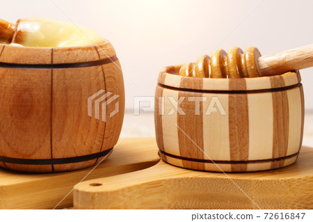wooden stick to bowl with liquid floral fresh honey. Healthy organic honey dripping, pouring from honey wooden spoon. wooden stick to bowl with liquid floral fresh honey. Healthy organic honey dripping, pouring from honey wooden spoon. 72616847