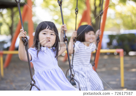 Girl playing on a swing with friends 72617587