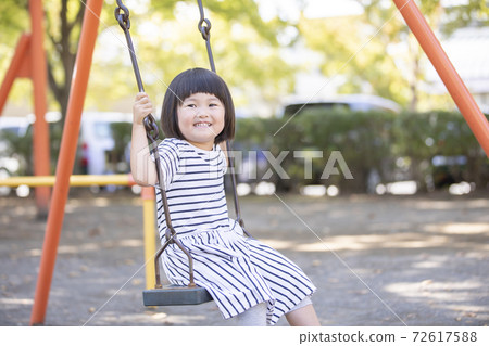 A girl playing with a swing A girl playing with a swing 72617588