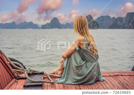 Attractive woman in a dress is traveling by boat in Halong Bay. Vietnam. Travel to Asia, happiness emotion, summer holiday concept. Picturesque sea landscape. Ha Long Bay, Vietnam 72619885