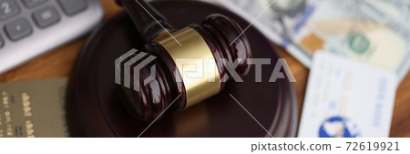Wooden gavel for judge lies on table next to one hundred dollar bills and bank credit cards. Wooden gavel for judge lies on table next to one hundred dollar bills and bank credit cards. 72619921