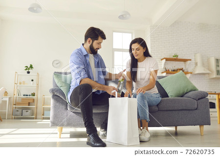 Young married couple received a food delivery and unpacked a package of groceries together. 72620735
