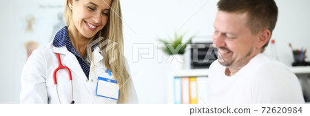Doctor and patient smile in medical office and fix kinesiotape on patient's knee joint Doctor and patient smile in medical office and fix kinesiotape on patient's knee joint 72620984