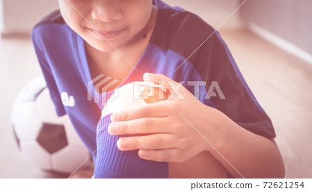 Little soccer playing looking at his bandage on his wound on the right knee. 72621254