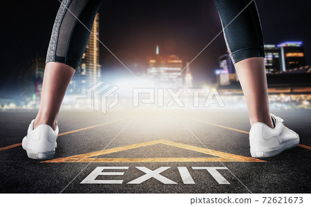 Woman standing on exit signage road for Business exit strategy concept with night city skyline background. Woman standing on exit signage road for Business exit strategy concept with night city skyline background. 72621673