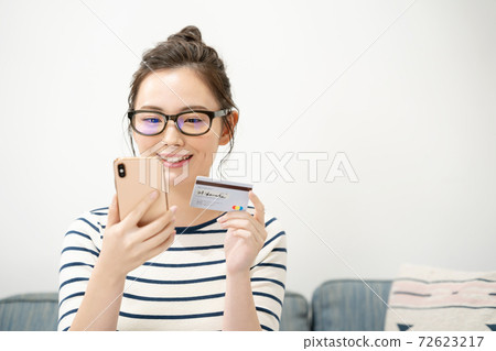 Young woman with smartphone and card Young woman with smartphone and card 72623217