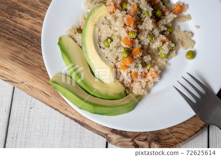 Quinoa porridge with vegetables and avocado in a white flat plate on a 72625614