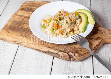 Quinoa porridge with vegetables and avocado in a white flat plate on a 72625615