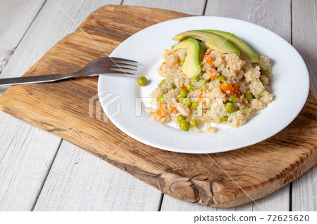 Quinoa porridge with vegetables and avocado in a white flat plate on a 72625620