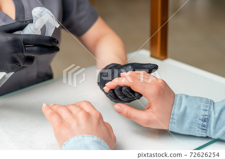 Manicurist applies spray. 72626254