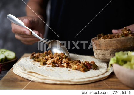man preparing a durum or a burrito 72626366