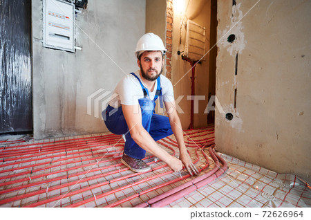 Bearded young man installing underfloor heating pipes. Bearded young man installing underfloor heating pipes. 72626964