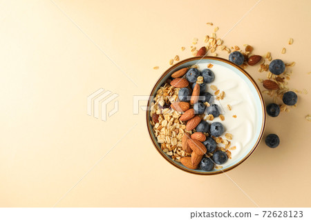 Bowl with tasty granola on beige background Bowl with tasty granola on beige background 72628123