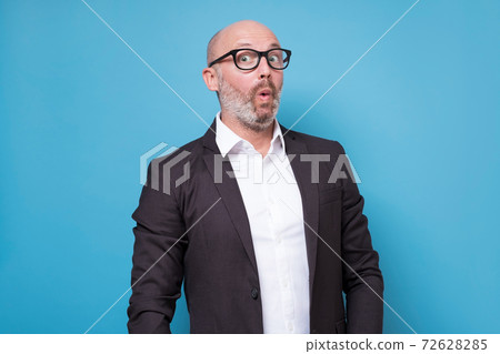 Mature hispanic man in suit with surprised face expression 72628285