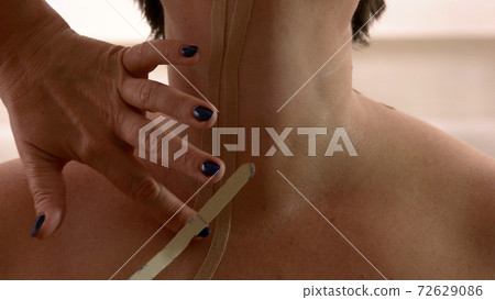 Female doctor applying kinesiology tape on female neck. 72629086