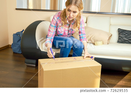 Girl writing on cardboard box. Girl writing on cardboard box. 72629535
