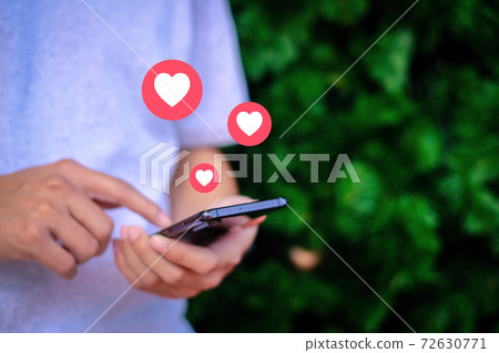 Man holding smartphone with love icon and christmas tree background, Technology concept. 72630771